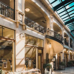 an interior photo of the south all of the Grove Arcade, the spiral staircase, and one of the shops.