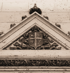 A close up photo of some of the architecture above the elevator lobby in the center arcade. A intricately designed shield surrounded with a triangle architecture