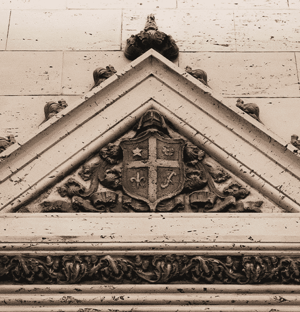 A close up photo of some of the architecture above the elevator lobby in the center arcade. A intricately designed shield surrounded with a triangle architecture