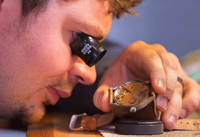 an employee closely examining a watch that needs to be repaired
